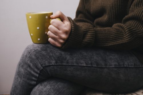 脚を組んでコーヒーを飲む男性